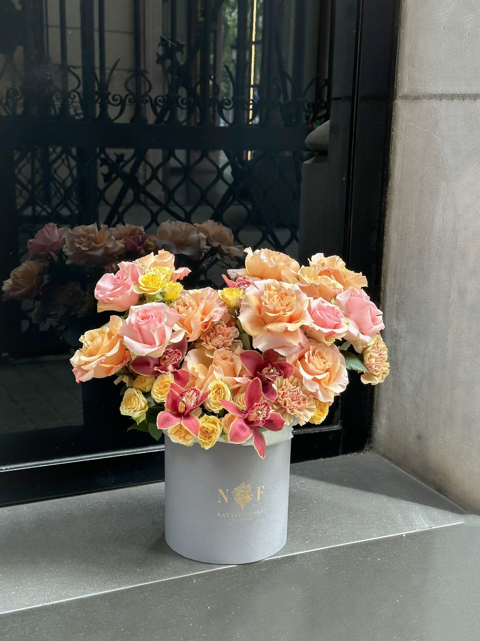 Rosas naranjas y orquídeas en caja